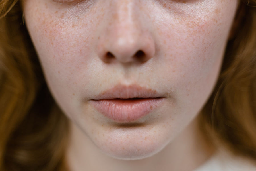 Woman looking calmly in a bathroom mirror while considering facial hair treatment options
